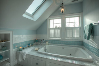 高級な広いビーチスタイルのおしゃれなマスターバスルーム (シェーカースタイル扉のキャビネット、白いキャビネット、ドロップイン型浴槽、コーナー設置型シャワー、青いタイル、白いタイル、セラミックタイル、大理石の洗面台、アンダーカウンター洗面器、青い壁、磁器タイルの床) の写真