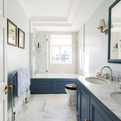 Mid-sized transitional master white tile and stone tile marble floor bathroom photo in London with recessed-panel cabinets, blue cabinets, blue walls, an undermount sink and marble countertops