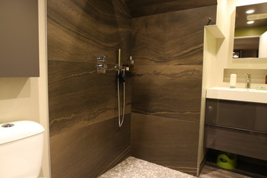 Example of a small minimalist 3/4 brown tile and porcelain tile porcelain tile and gray floor corner shower design in Edmonton with flat-panel cabinets, gray cabinets, a two-piece toilet, green walls, an integrated sink, solid surface countertops and a hinged shower door