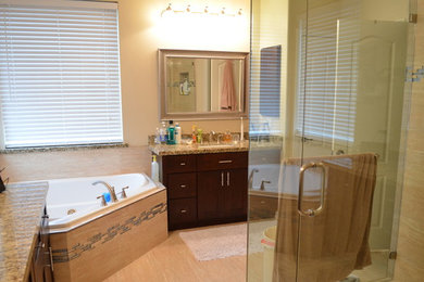 ダラスにある高級な広いコンテンポラリースタイルのおしゃれなマスターバスルーム (フラットパネル扉のキャビネット、濃色木目調キャビネット、ドロップイン型浴槽、オープン型シャワー、一体型トイレ	、ベージュのタイル、茶色いタイル、大理石タイル、ベージュの壁、淡色無垢フローリング、オーバーカウンターシンク、大理石の洗面台、オープンシャワー) の写真