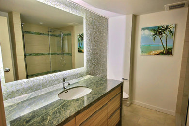 Exemple d'une salle de bain tendance en bois brun avec un lavabo encastré, un placard à porte plane, un plan de toilette en granite et un carrelage vert.