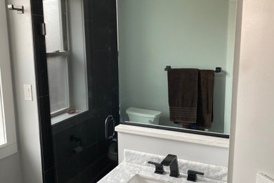 Imagen de cuarto de baño único y de pie pequeño con baldosas y/o azulejos negros, baldosas y/o azulejos de porcelana, aseo y ducha y ducha con puerta con bisagras