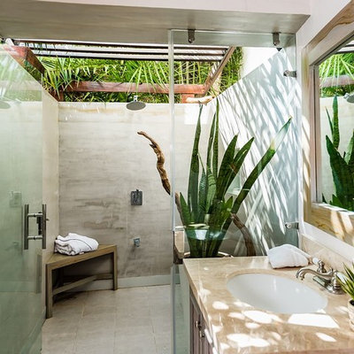 Example of an island style gray tile gray floor wet room design in Other with dark wood cabinets, white walls, an undermount sink, a hinged shower door and beige countertops