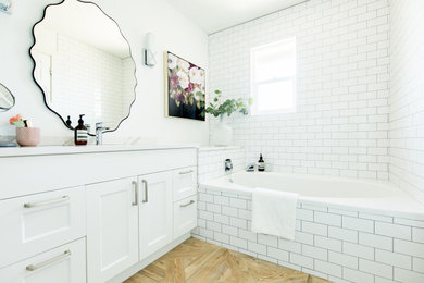 Alcove bathtub - transitional 3/4 light wood floor, beige floor and single-sink alcove bathtub idea in Vancouver with shaker cabinets, white cabinets, white walls, an undermount sink, white countertops and a built-in vanity