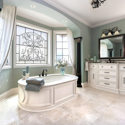 Inspiration for a large timeless master beige tile travertine floor freestanding bathtub remodel in Milwaukee with white cabinets, an undermount sink, recessed-panel cabinets, a one-piece toilet and green walls