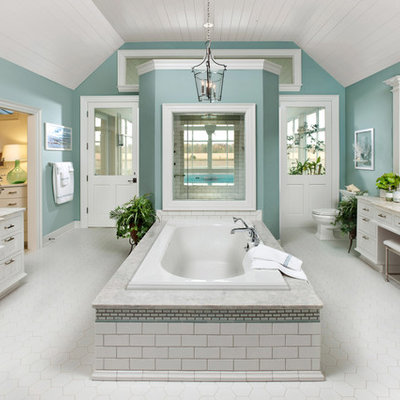 Example of a large classic master white tile and ceramic tile ceramic tile drop-in bathtub design in Milwaukee with a drop-in sink, flat-panel cabinets, white cabinets, granite countertops, a one-piece toilet, green walls and beige countertops