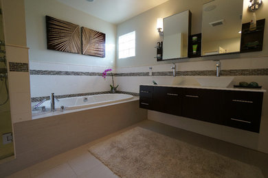 Example of a mid-sized trendy master gray tile and porcelain tile porcelain tile and beige floor bathroom design in San Diego with flat-panel cabinets, dark wood cabinets, beige walls, a vessel sink, solid surface countertops and a hinged shower door
