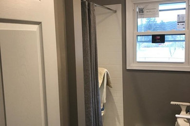 Inspiration for a mid-sized transitional gray tile and porcelain tile porcelain tile walk-in shower remodel in Philadelphia with white cabinets, a two-piece toilet, gray walls, an undermount sink, solid surface countertops and recessed-panel cabinets