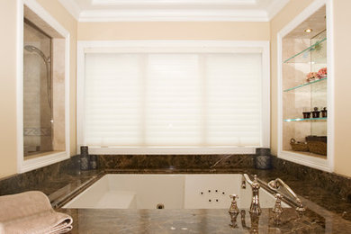 Cette image montre une très grande salle de bain principale traditionnelle en bois brun avec un plan de toilette en marbre, une baignoire encastrée, une douche double, un carrelage marron, un lavabo encastré, WC séparés et un mur gris.
