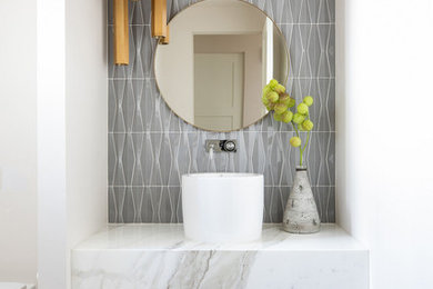 Small trendy gray tile and ceramic tile light wood floor and single-sink bathroom photo in Sacramento with white cabinets, a wall-mount toilet, white walls, a pedestal sink, marble countertops, white countertops and a floating vanity