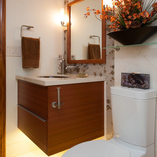 Immagine di una stanza da bagno tropicale con ante lisce, ante in legno scuro, WC a due pezzi, piastrelle bianche, piastrelle di vetro, pareti beige, pavimento in pietra calcarea, lavabo sottopiano e top in quarzo composito