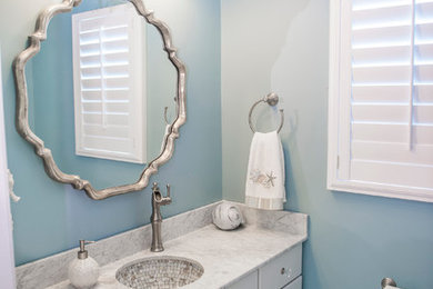 Example of a mid-sized beach style 3/4 mosaic tile marble floor bathroom design in Philadelphia with raised-panel cabinets, white cabinets, marble countertops, blue walls, a two-piece toilet and an undermount sink
