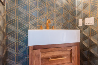 Example of a small transitional 3/4 medium tone wood floor, brown floor, single-sink and wallpaper bathroom design in Providence with recessed-panel cabinets, medium tone wood cabinets, blue walls, a console sink and a freestanding vanity