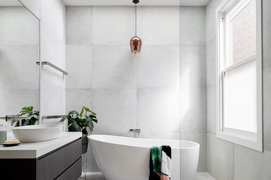 Photo of a medium sized contemporary grey and black ensuite bathroom in Melbourne with flat-panel cabinets, dark wood cabinets, a freestanding bath, grey tiles, engineered stone worktops, grey floors, an open shower, a built-in shower and a vessel sink.