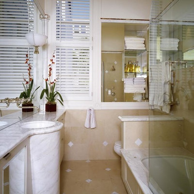 Example of a classic bathroom design in Other with marble countertops and an undermount tub