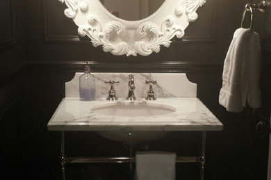 Ejemplo de cuarto de baño clásico renovado con lavabo bajoencimera, encimera de mármol, sanitario de una pieza, baldosas y/o azulejos de porcelana, paredes negras y suelo de baldosas de porcelana