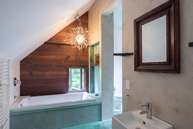 Modelo de cuarto de baño principal contemporáneo de tamaño medio con bañera empotrada, baldosas y/o azulejos marrones, paredes grises, suelo de cemento, lavabo suspendido y suelo azul
