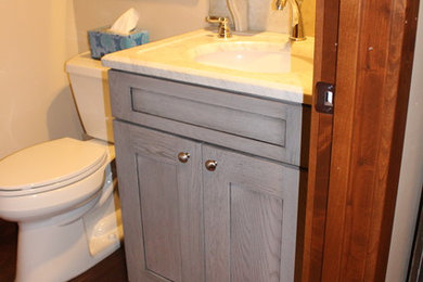 Modelo de cuarto de baño industrial con armarios estilo shaker, puertas de armario grises, baldosas y/o azulejos de mármol, aseo y ducha, lavabo tipo consola, encimera de ónix y suelo marrón