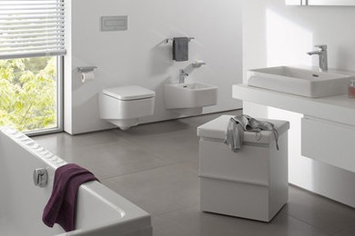 Réalisation d'une grande salle de bain principale minimaliste avec une vasque, un placard à porte plane, des portes de placard blanches, une baignoire indépendante, WC suspendus et un mur blanc.