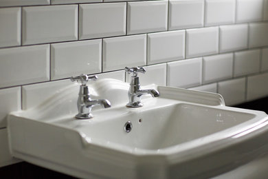 This is an example of a classic bathroom in London with white tiles and a wall-mounted sink.