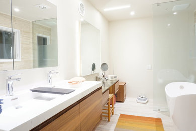 Medium sized contemporary ensuite bathroom in DC Metro with flat-panel cabinets, medium wood cabinets, a freestanding bath, a built-in shower, a one-piece toilet, white tiles, white walls, an integrated sink, solid surface worktops and grey floors.