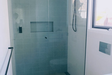 Mid-sized minimalist master gray tile and ceramic tile ceramic tile, gray floor and single-sink doorless shower photo in Melbourne with light wood cabinets, a one-piece toilet, white walls, an integrated sink, a hinged shower door and a freestanding vanity