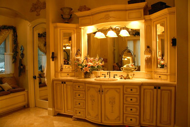 Diseño de cuarto de baño principal clásico grande con armarios con paneles con relieve, puertas de armario beige, paredes beige, suelo de travertino, lavabo encastrado, encimera de granito y suelo marrón