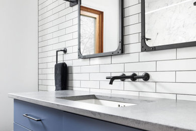 Example of a mid-sized urban white tile porcelain tile and gray floor bathroom design in Toronto with flat-panel cabinets, blue cabinets, white walls, an undermount sink, gray countertops and concrete countertops