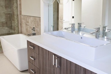 Large contemporary ensuite bathroom in Los Angeles with flat-panel cabinets, brown cabinets, a freestanding bath, an alcove shower, beige walls, porcelain flooring, a trough sink, solid surface worktops, beige floors, a hinged door and white worktops.