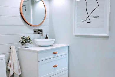 Example of a terrazzo floor and white floor bathroom design in Other with white cabinets, a one-piece toilet, gray walls, a vessel sink, quartz countertops and white countertops