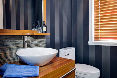 Aménagement d'une petite salle d'eau contemporaine en bois brun avec une vasque, un placard à porte plane, WC à poser, un carrelage gris, des carreaux de porcelaine, un sol en carrelage de porcelaine, un plan de toilette en bois, un mur bleu et un plan de toilette marron.