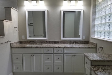 Modelo de cuarto de baño principal clásico renovado de tamaño medio con armarios con paneles empotrados, puertas de armario blancas, paredes blancas, lavabo bajoencimera y encimera de granito