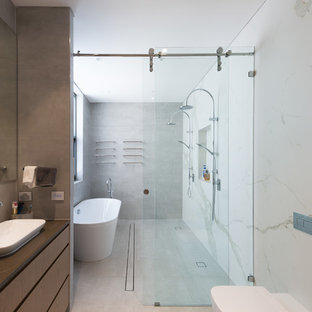Large contemporary wet room bathroom in Sydney with flat-panel cabinets, medium wood cabinets, a freestanding tub, white tile, stone slab, a vessel sink, grey floor and grey benchtops.