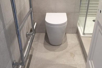 Small contemporary shower room bathroom in London with flat-panel cabinets, white cabinets, a built-in shower, a one-piece toilet, grey tiles, ceramic tiles, grey walls, porcelain flooring, a wall-mounted sink, quartz worktops, grey floors, a hinged door and white worktops.