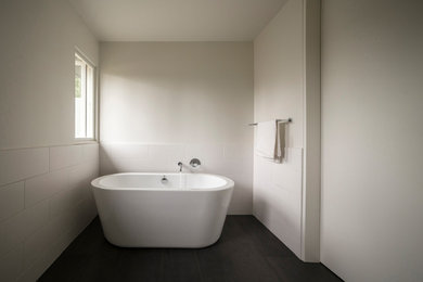 Idee per una stanza da bagno padronale minimalista di medie dimensioni con vasca freestanding, piastrelle bianche, piastrelle in ceramica, pareti bianche, pavimento con piastrelle in ceramica e pavimento nero