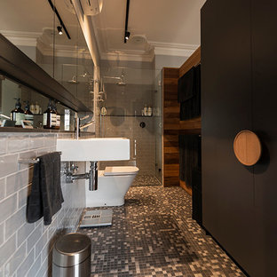 Photo of a large traditional master bathroom in Melbourne with flat-panel cabinets, black cabinets, an alcove shower, a two-piece toilet, gray tile, subway tile, grey walls, mosaic tile floors, a wall-mount sink, tile benchtops, grey floor and a hinged shower door.