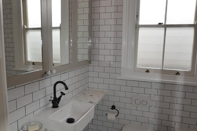 シドニーにあるお手頃価格のトラディショナルスタイルのおしゃれな浴室 (一体型シンク、アルコーブ型浴槽、シャワー付き浴槽	、落し込みパネル扉のキャビネット、大理石の洗面台、白いタイル、サブウェイタイル) の写真