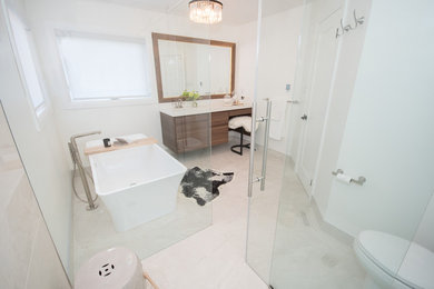 Large contemporary ensuite bathroom in Toronto with flat-panel cabinets, medium wood cabinets, a freestanding bath, a built-in shower, a one-piece toilet, white tiles, porcelain tiles, white walls, porcelain flooring, a submerged sink, engineered stone worktops, white floors, a sliding door and white worktops.