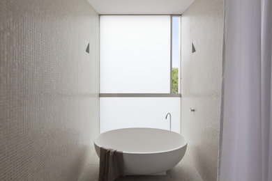 Modelo de cuarto de baño minimalista con bañera exenta y baldosas y/o azulejos en mosaico
