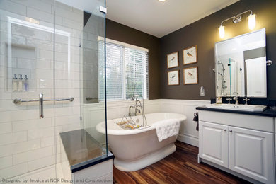 Mid-sized elegant master medium tone wood floor bathroom photo in Seattle with raised-panel cabinets, white cabinets, green walls, a drop-in sink, granite countertops, a hinged shower door and black countertops