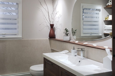 Photo of a small traditional family bathroom in New York with shaker cabinets, medium wood cabinets, an alcove bath, a one-piece toilet, beige tiles, porcelain tiles, beige walls, porcelain flooring, an integrated sink, solid surface worktops and brown floors.