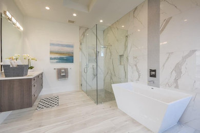 Large trendy master white tile marble floor and white floor bathroom photo in Miami with flat-panel cabinets, medium tone wood cabinets, white walls, solid surface countertops and a hinged shower door