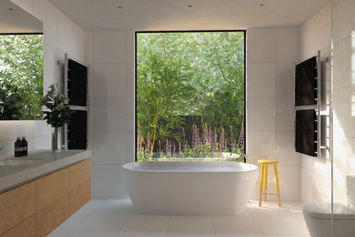 Cette photo montre une salle de bain tendance en bois clair de taille moyenne avec un lavabo encastré, un placard à porte plane, un plan de toilette en quartz modifié, une baignoire indépendante, une douche ouverte, WC à poser et un carrelage blanc.