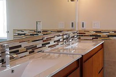 Photo of a large ensuite bathroom in Orlando with raised-panel cabinets, medium wood cabinets, beige tiles, black tiles, black and white tiles, brown tiles, multi-coloured tiles, white tiles, ceramic tiles, beige walls and a built-in sink.