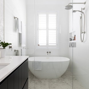 Transitional 3/4 wet room bathroom in Brisbane with raised-panel cabinets, black cabinets, a freestanding tub, white tile, white walls, an undermount sink, engineered quartz benchtops, grey floor, a hinged shower door, white benchtops, a single vanity and a built-in vanity.