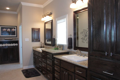 Foto de cuarto de baño tradicional con lavabo encastrado, armarios con paneles con relieve, puertas de armario de madera en tonos medios y encimera de granito