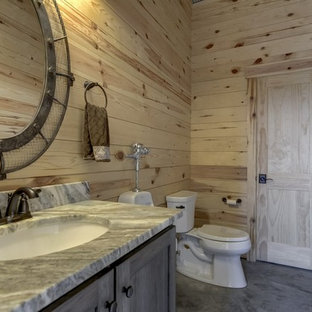 Ispirazione per una stanza da bagno con doccia country di medie dimensioni con ante con riquadro incassato, ante grigie, orinatoio, pareti beige, pavimento in cemento, lavabo sottopiano, top in pietra calcarea, pavimento grigio e top grigio