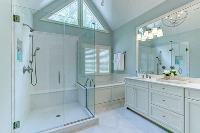 Example of a large trendy master porcelain tile and gray floor corner shower design in Raleigh with recessed-panel cabinets, white cabinets, an undermount tub, blue walls, an undermount sink, solid surface countertops, a hinged shower door and a two-piece toilet