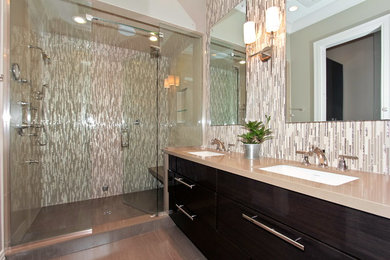 Diseño de cuarto de baño principal grande con lavabo integrado, puertas de armario de madera en tonos medios, ducha abierta, sanitario de una pieza, azulejos en listel, paredes grises y armarios con paneles lisos