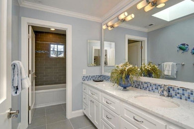 Modelo de cuarto de baño contemporáneo con lavabo bajoencimera, armarios estilo shaker, puertas de armario blancas, encimera de mármol, bañera empotrada, combinación de ducha y bañera, sanitario de una pieza, baldosas y/o azulejos grises y baldosas y/o azulejos en mosaico